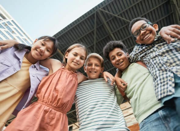 Group of smiling girls and boys with around around each other