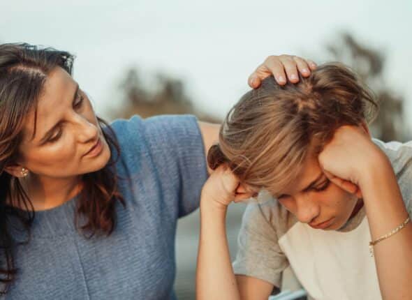 Mother comforts her upset young son by touching his hair