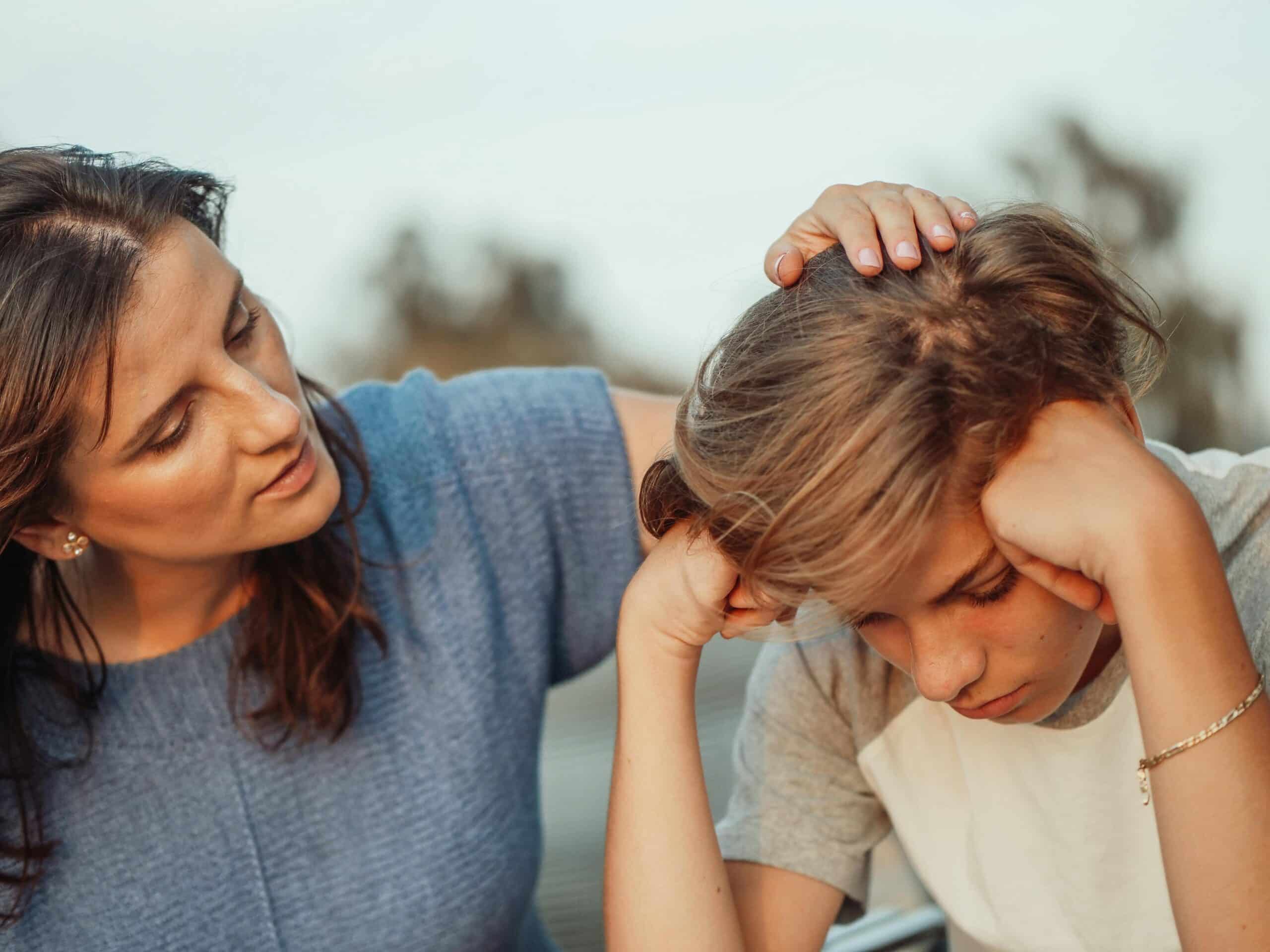Mother comforts her upset young son by touching his hair