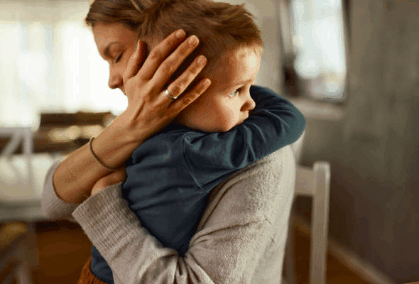 Mother consoling her young son with a sad expression on his face.
