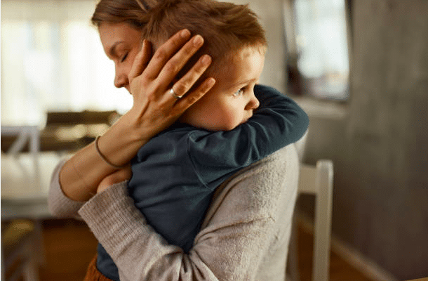 Mother consoling her young son with a sad expression on his face.