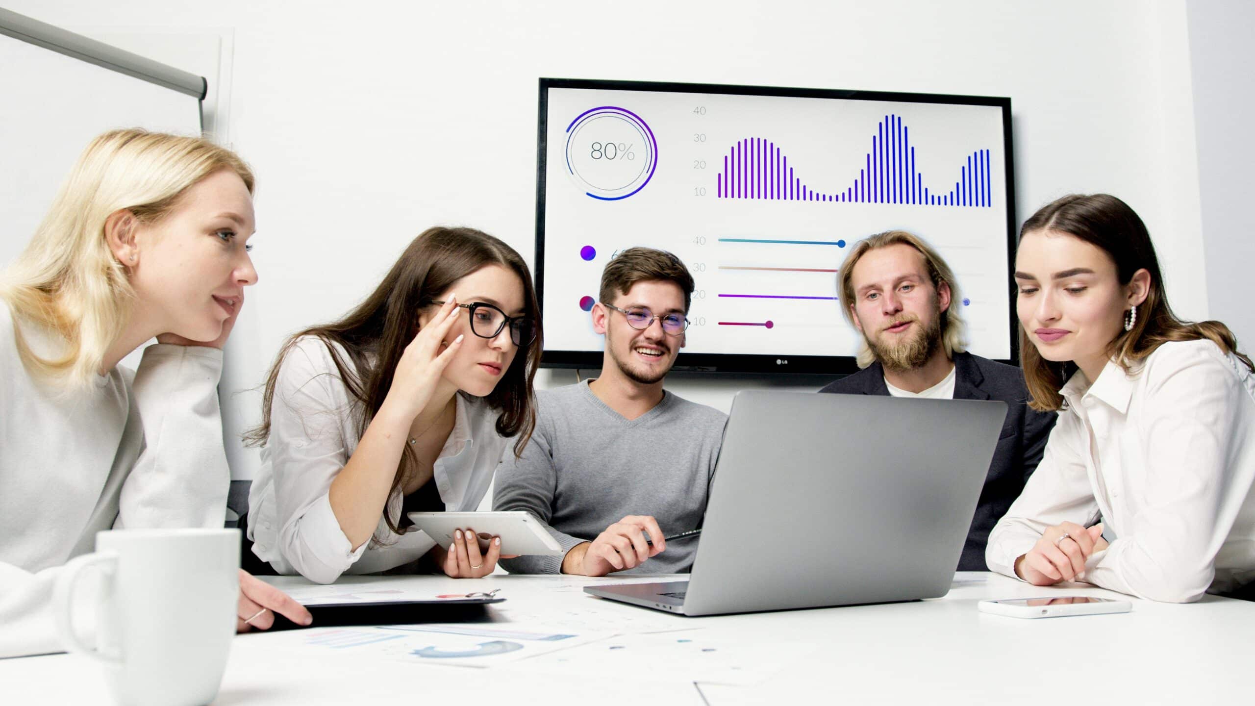 Group of young employees smiling and looking at laptop.