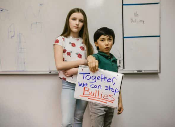 Two students holding a sign that says "Together we can stop bullies"
