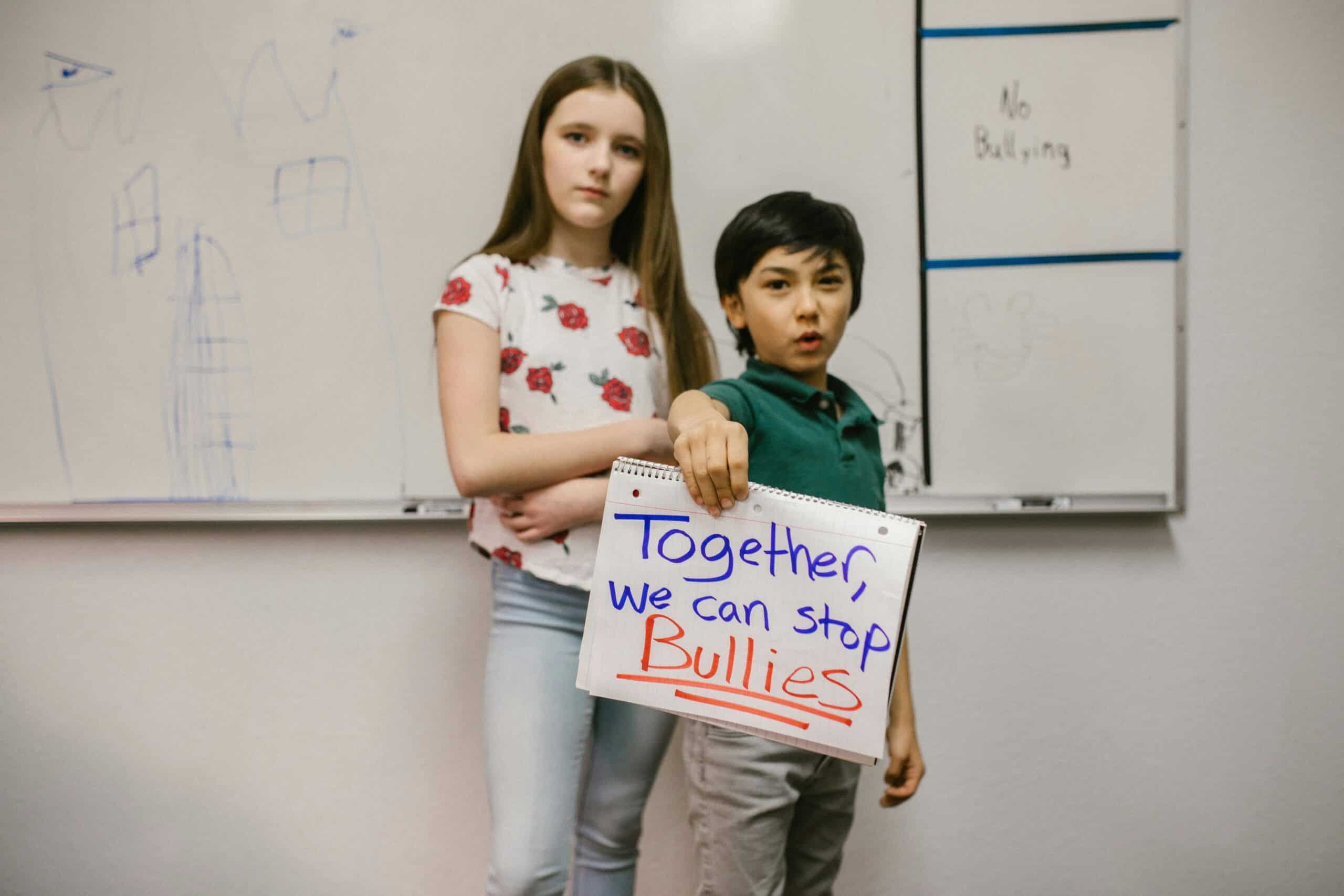 Two students holding a sign that says "Together we can stop bullies"