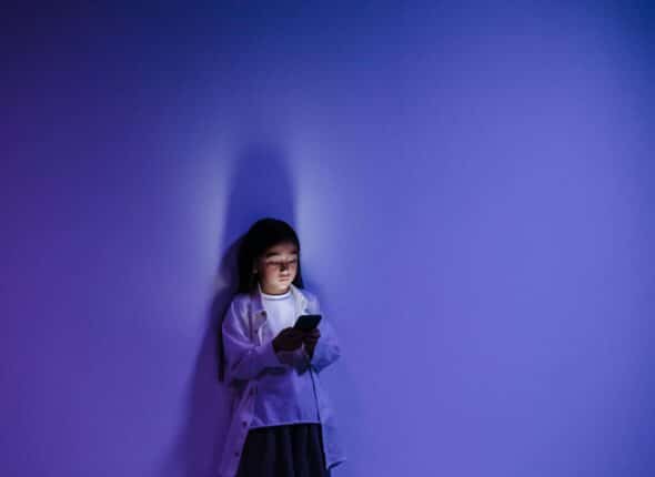 young boy looking at mobile phone alone in the dark.
