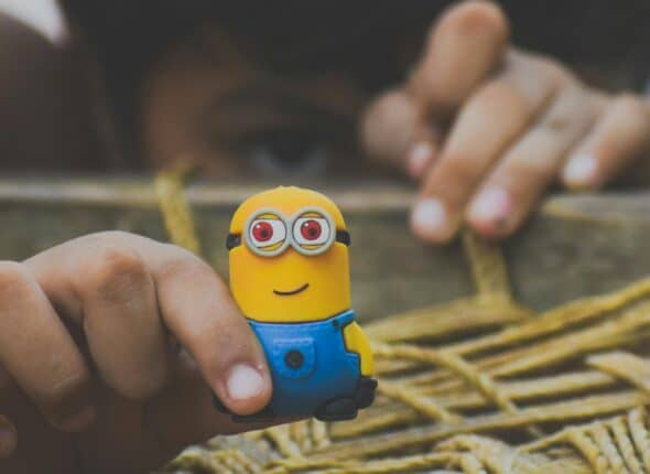 Close up of a child playing with a toy minion figurine that is smiling