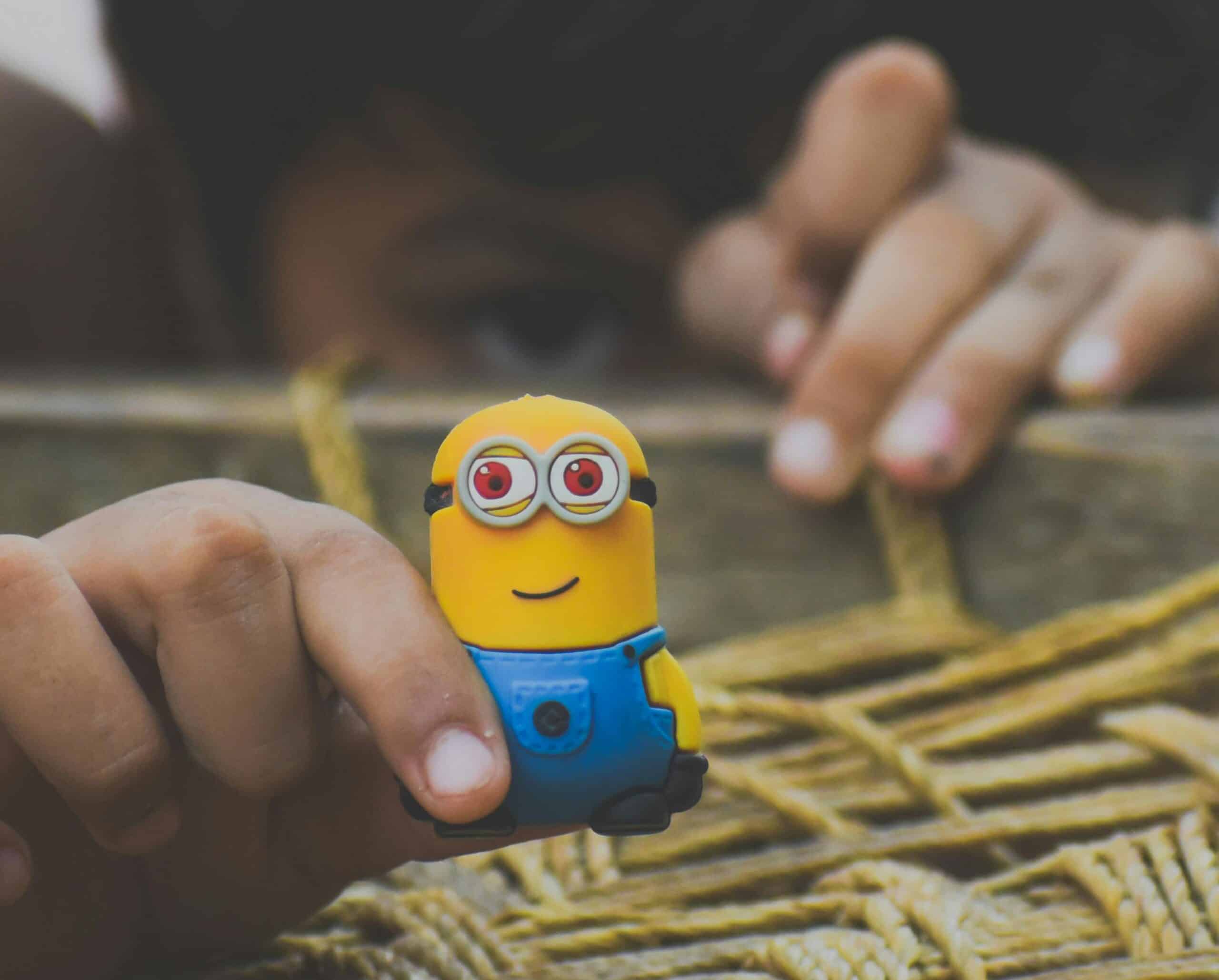 Close up of a child playing with a toy minion figurine that is smiling