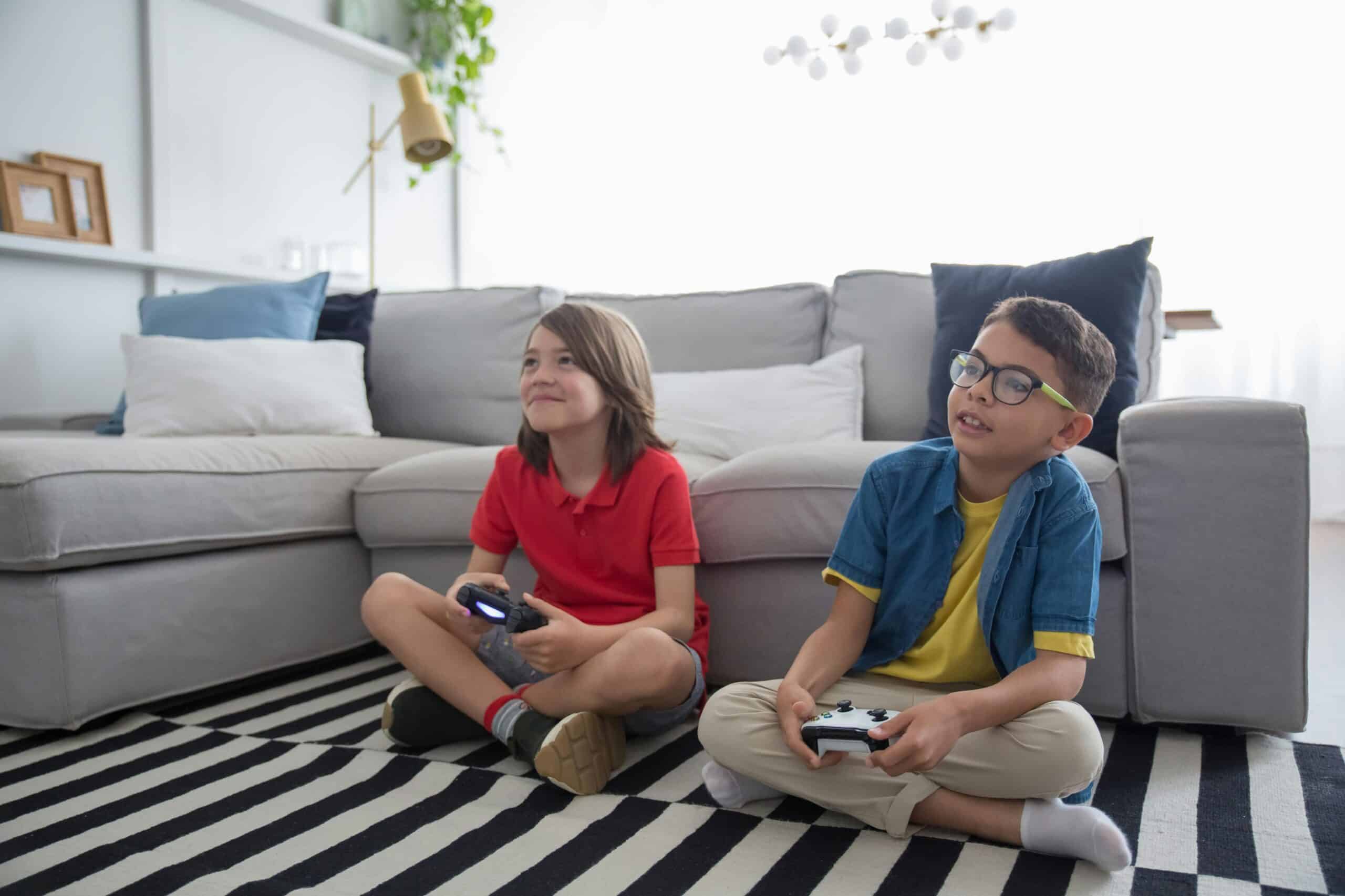 Two young boys sitting on the floor while gaming.