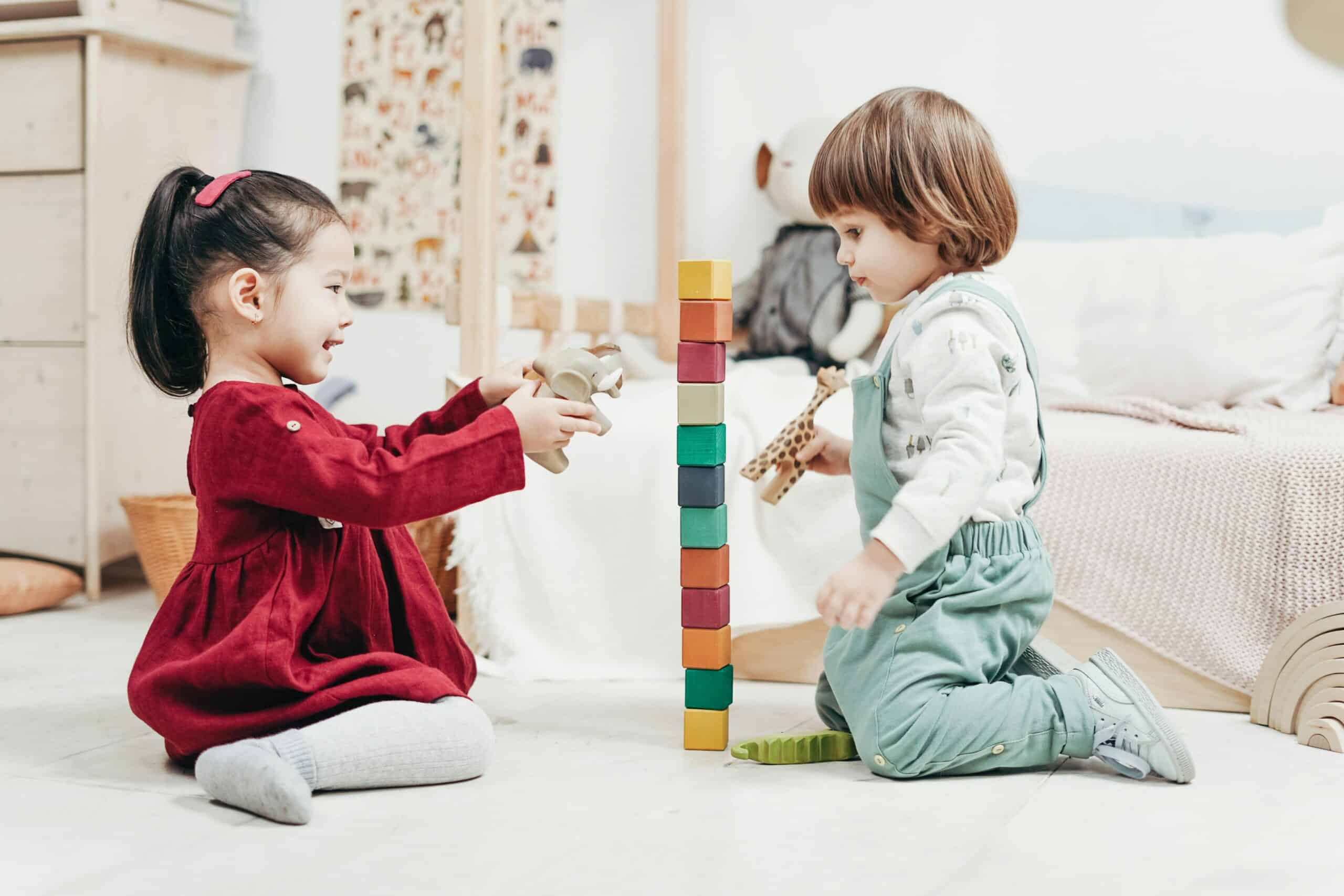 A girl and boy preschool children playing with toys on the floor